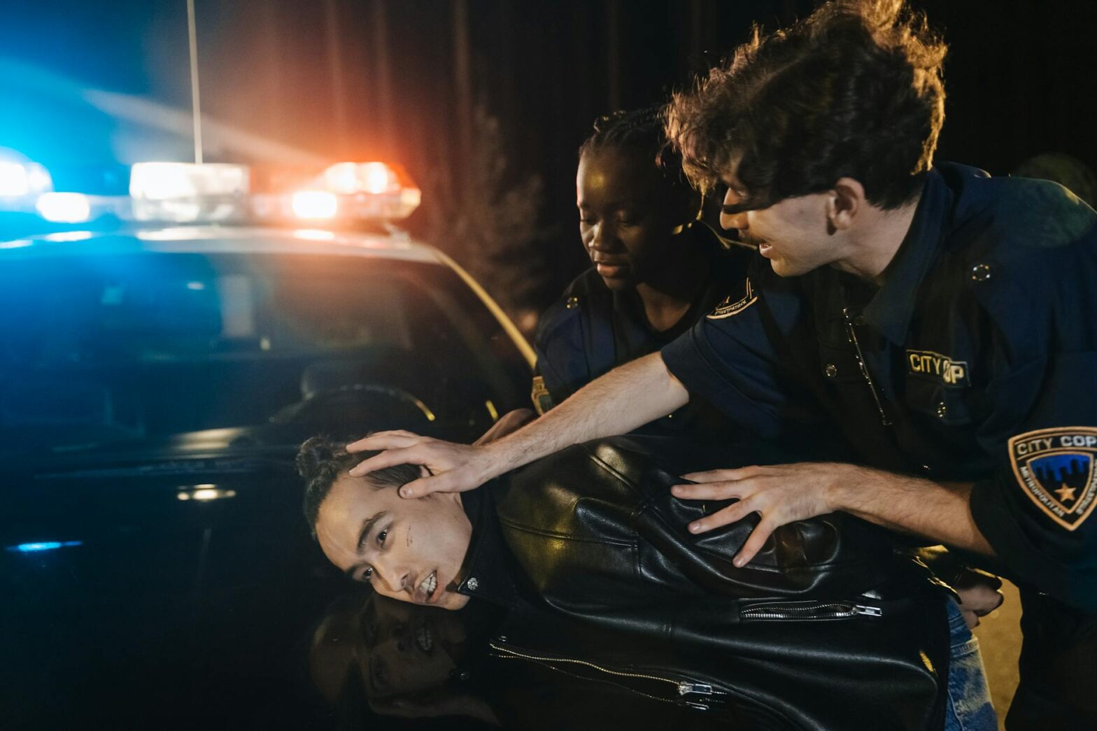 man in police uniform arresting a man in black leather jacker